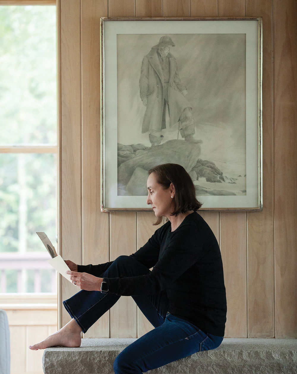 In her Pemaquid home, Jamie Hanna examines sketches by her father, David Hanna, whose untitled pencil drawing hangs on the wall.